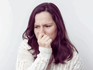homeowner holding her nose because of strange odors coming from heater