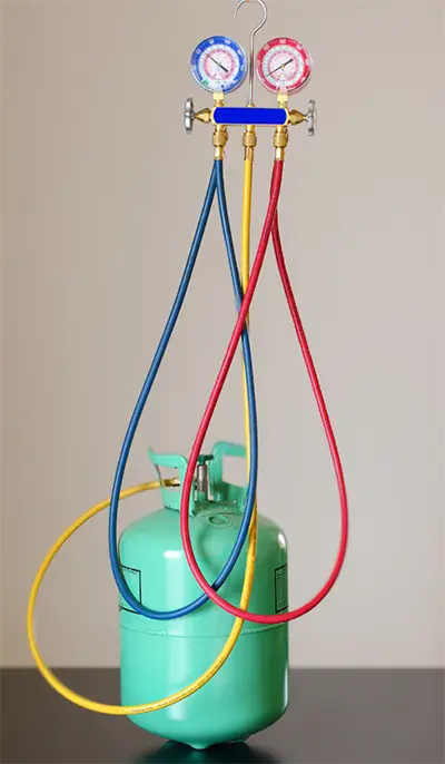A canister of Freon with a manifold gauge and hoses attached