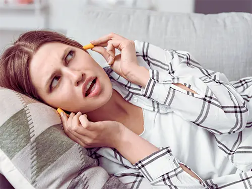 Homeowner plugging her hears from the loud noises coming from her AC unit