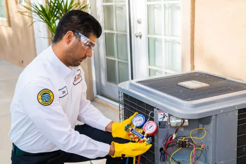 One Hour AC Tech using a manifold gauge on a condenser unit outside of an Orlando home