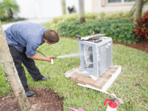 homeowner cleaning heat pump as a part of their DIY maintenance routine