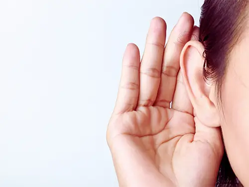 Closeup of a female ear and hand gesturing to listen out for sounds coming from an HVAC system